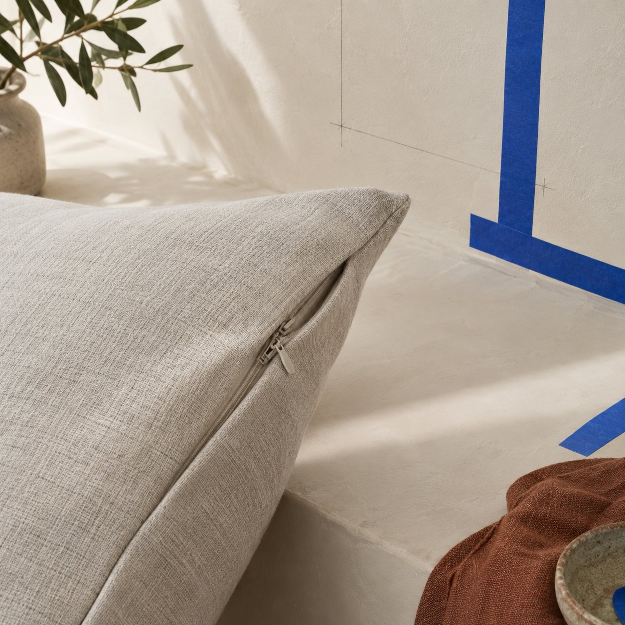 A cushion cover hidden zip and seam on a plaster surface